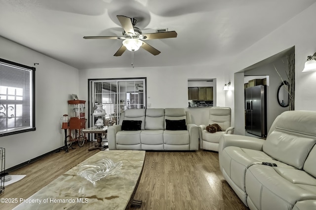 living area with baseboards, ceiling fan, and wood finished floors