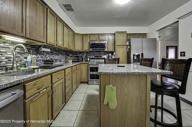 kitchen featuring visible vents, a kitchen island, light tile patterned floors, appliances with stainless steel finishes, and a sink