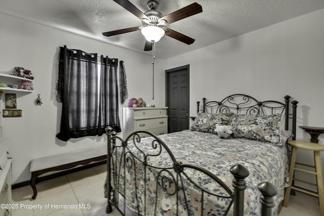 bedroom with ceiling fan, baseboards, a textured ceiling, and light tile patterned flooring