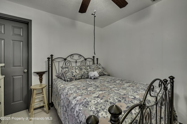 bedroom featuring ceiling fan, light tile patterned flooring, and a textured ceiling