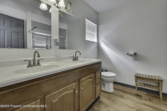 full bath with toilet, wood finished floors, a shower with door, and a sink