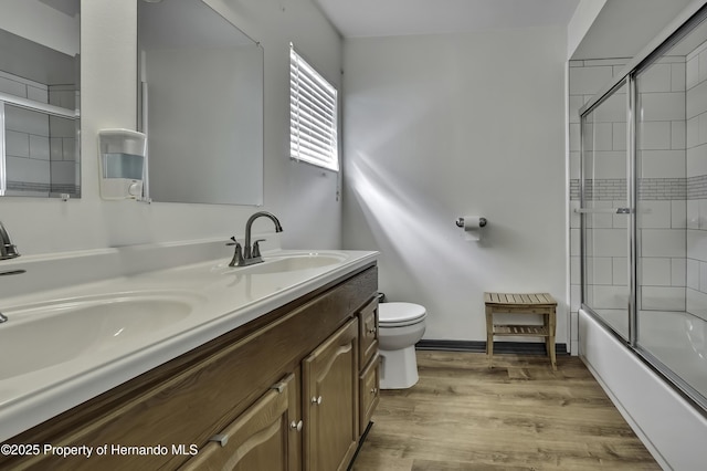 bathroom featuring a sink, toilet, wood finished floors, and double vanity