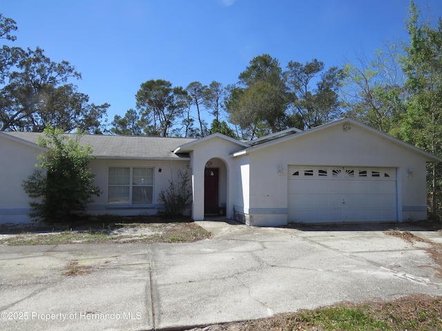 ranch-style home with concrete driveway, an attached garage, and stucco siding