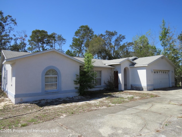 ranch-style house featuring stucco siding, an attached garage, and driveway