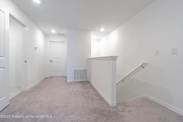 corridor featuring visible vents, an upstairs landing, carpet, and baseboards