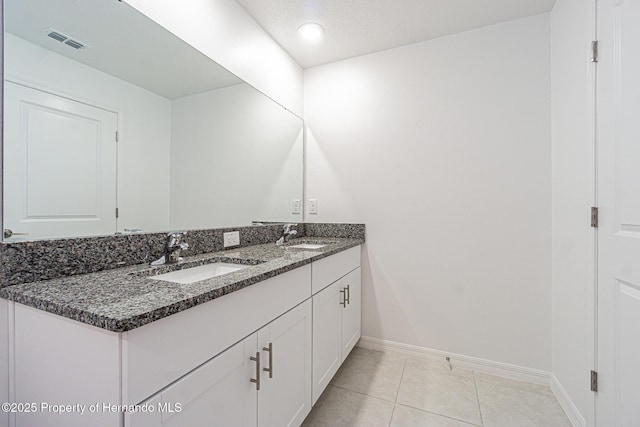 bathroom featuring visible vents, a sink, tile patterned flooring, double vanity, and baseboards