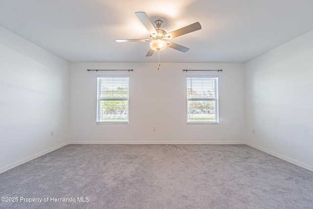 carpeted empty room featuring baseboards, a wealth of natural light, and ceiling fan