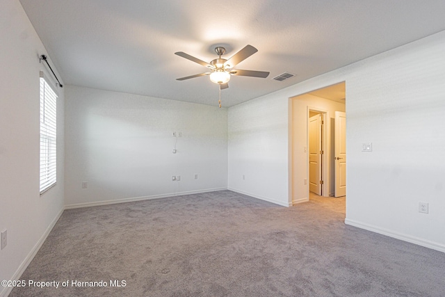 empty room featuring visible vents, carpet flooring, baseboards, and a ceiling fan