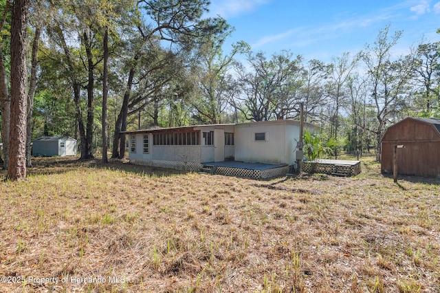 rear view of property with a storage shed and an outdoor structure