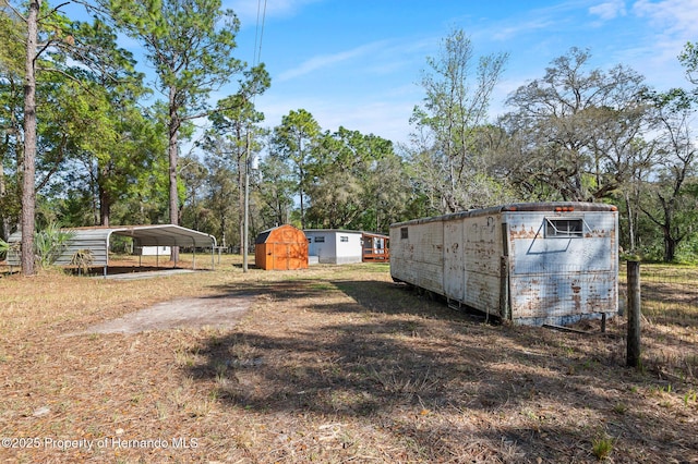 view of yard with a carport, an outdoor structure, a shed, and dirt driveway