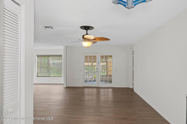 unfurnished room with visible vents, a ceiling fan, a textured ceiling, wood finished floors, and french doors