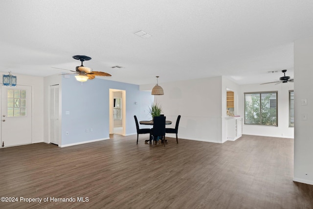 unfurnished living room featuring baseboards, visible vents, dark wood-style flooring, ceiling fan, and a textured ceiling