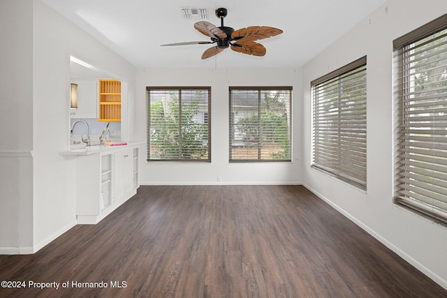 unfurnished living room with visible vents, a sink, baseboards, ceiling fan, and dark wood-style flooring