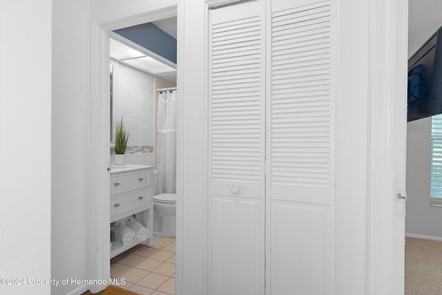 full bath featuring vanity, toilet, a closet, and tile patterned flooring