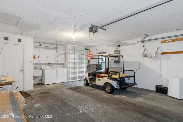 garage featuring a sink, electric panel, a garage door opener, and washer and clothes dryer