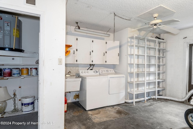 clothes washing area with washing machine and dryer, water heater, cabinet space, a textured ceiling, and a ceiling fan