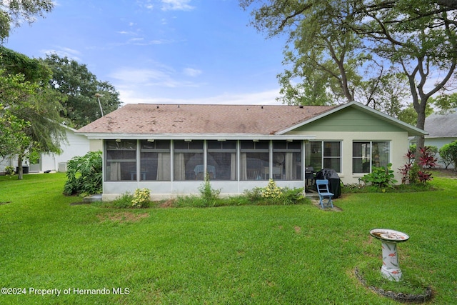 back of property with a yard and a sunroom