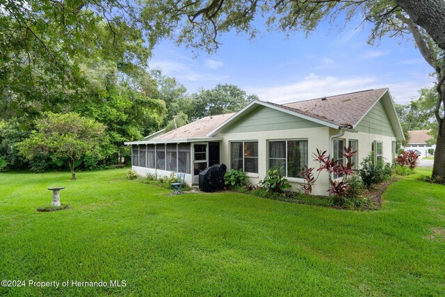 rear view of house featuring a lawn and a sunroom