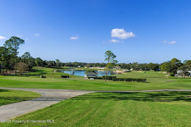 view of property's community featuring a yard, a water view, and view of golf course