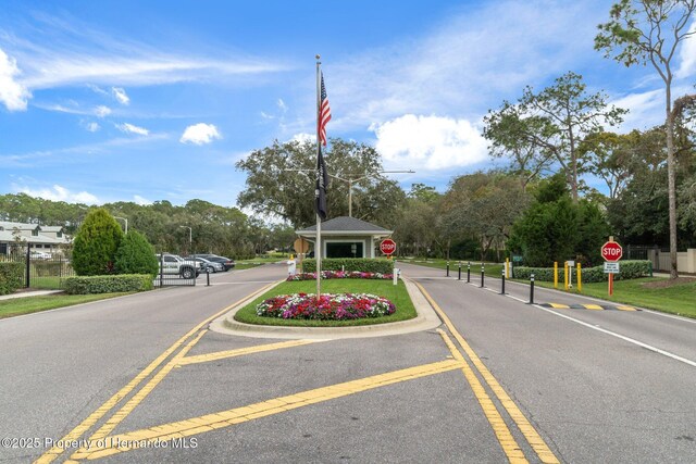 view of road featuring a gated entry, traffic signs, and street lighting