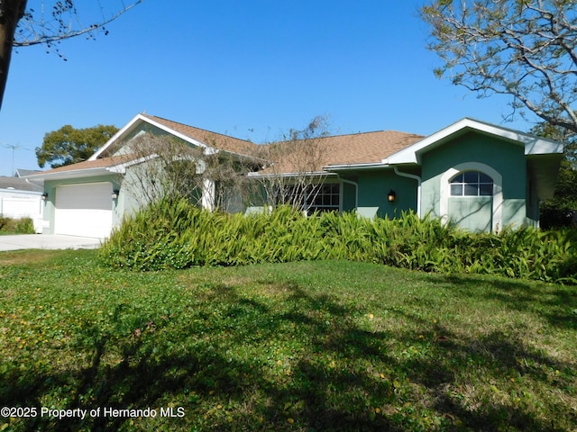 single story home featuring stucco siding, an attached garage, driveway, and a front yard