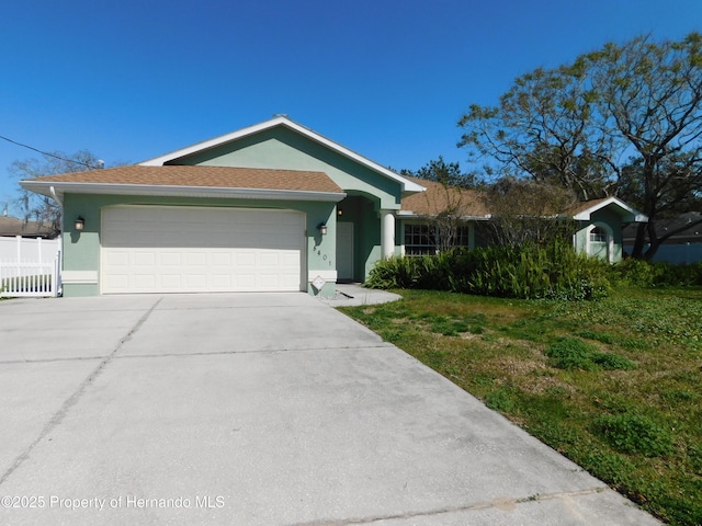 single story home featuring fence, driveway, an attached garage, stucco siding, and a front lawn