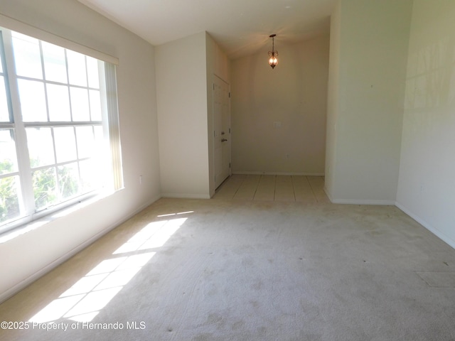 spare room featuring a chandelier and carpet