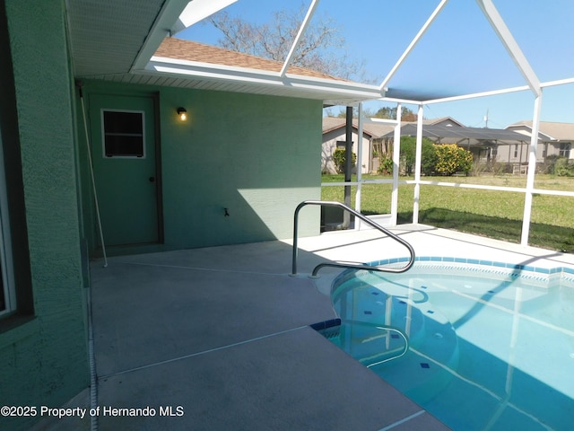 view of swimming pool featuring glass enclosure, a patio, and a yard