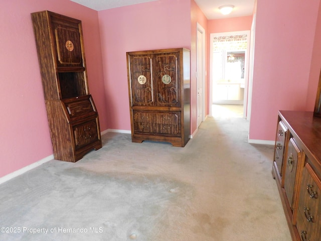 hallway featuring baseboards and carpet floors