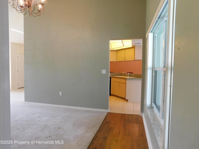 corridor with a chandelier, baseboards, and a sink