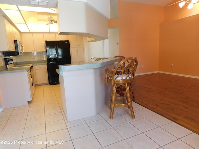 kitchen featuring white range with electric cooktop, a peninsula, light tile patterned flooring, ceiling fan, and black fridge with ice dispenser