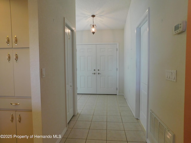 hallway featuring light tile patterned floors, visible vents, and baseboards