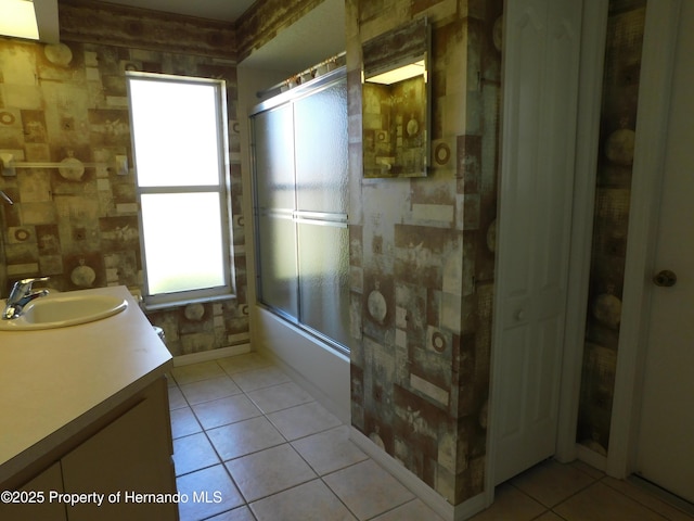 full bath featuring tile patterned flooring, plenty of natural light, combined bath / shower with glass door, and vanity