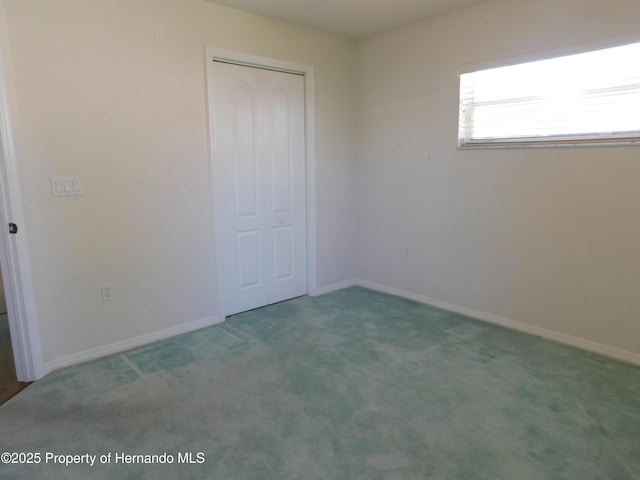 unfurnished bedroom with a closet, baseboards, and carpet