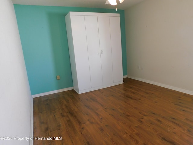 unfurnished bedroom with a closet, baseboards, and wood finished floors