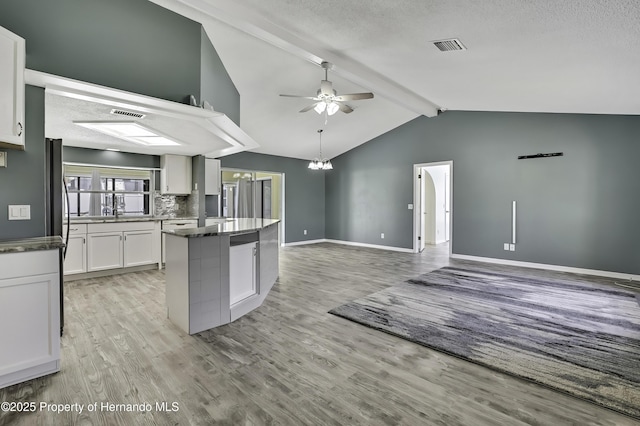 kitchen with light wood-type flooring, a center island, vaulted ceiling with beams, and ceiling fan with notable chandelier