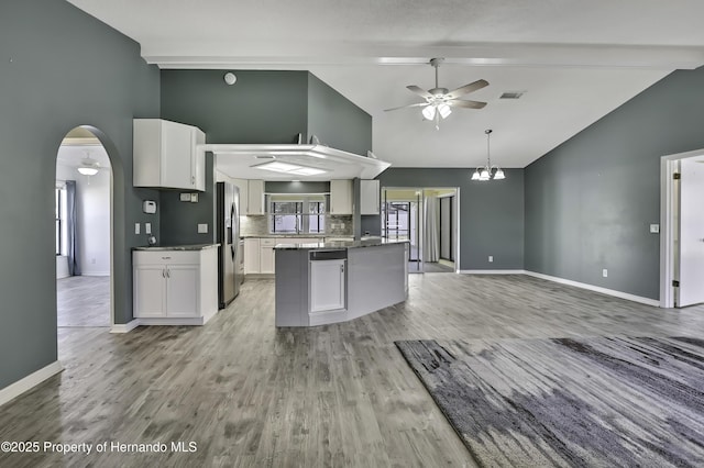 kitchen featuring visible vents, baseboards, stainless steel refrigerator with ice dispenser, high vaulted ceiling, and ceiling fan with notable chandelier