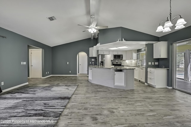 kitchen with stainless steel appliances, wood finished floors, visible vents, arched walkways, and ceiling fan with notable chandelier
