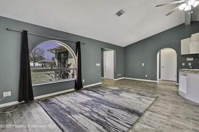 unfurnished living room featuring wood finished floors, visible vents, lofted ceiling, and ceiling fan