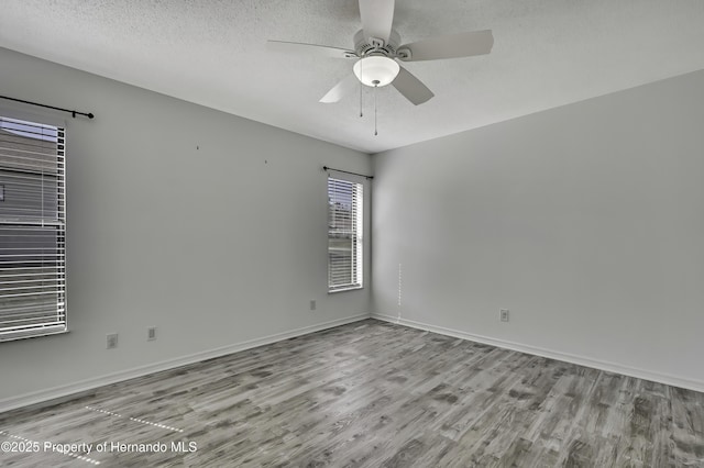 spare room with ceiling fan, baseboards, wood finished floors, and a textured ceiling