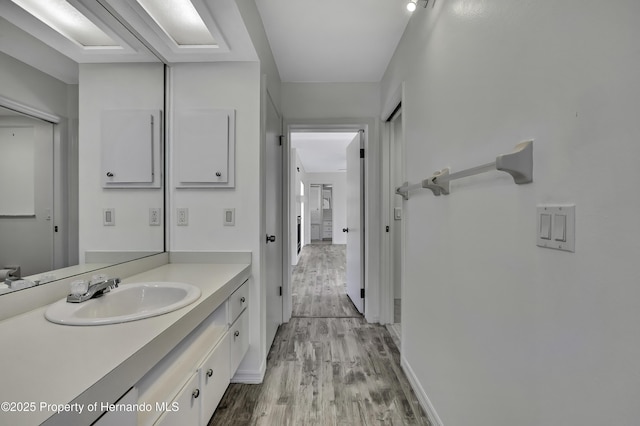 bathroom with baseboards, wood finished floors, and vanity