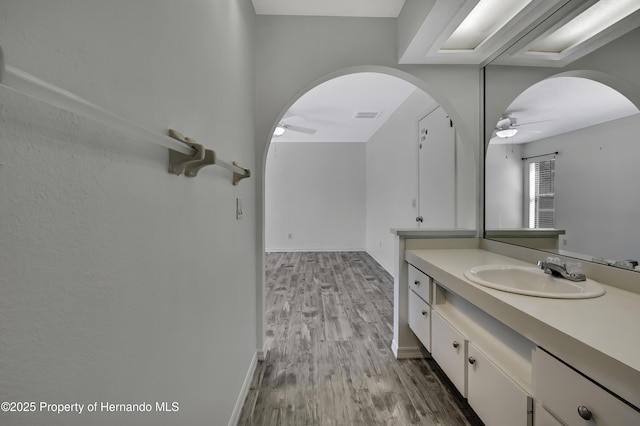 bathroom with wood finished floors, visible vents, vanity, baseboards, and ceiling fan