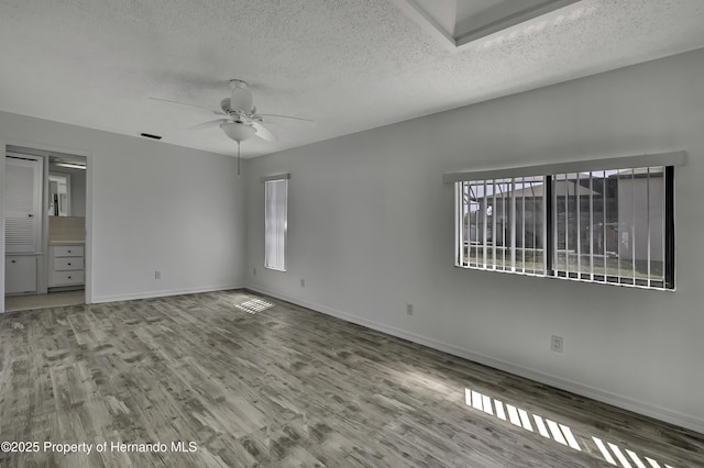 unfurnished bedroom featuring wood finished floors, baseboards, and multiple windows