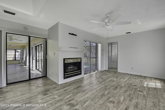 unfurnished living room with a ceiling fan, wood finished floors, and a healthy amount of sunlight