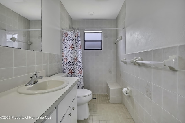 bathroom with tiled shower, toilet, tile patterned flooring, and tile walls