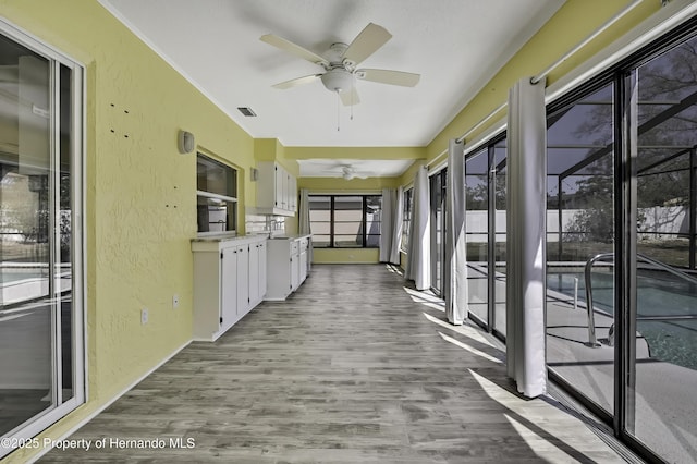 unfurnished sunroom with visible vents and ceiling fan