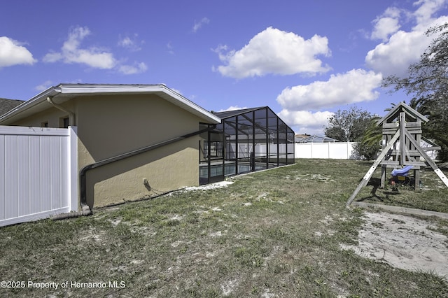 view of yard with a lanai, a fenced backyard, a swimming pool, and a playground