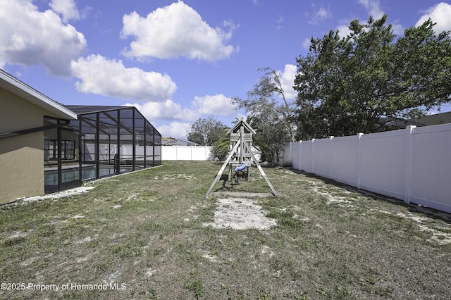 view of yard with a fenced backyard, a pool, and glass enclosure