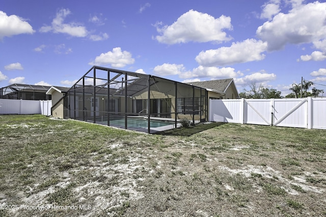 exterior space with a gate, an outdoor pool, a lawn, and a fenced backyard