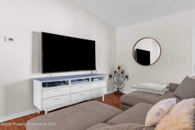 living area featuring lofted ceiling, baseboards, and wood finished floors